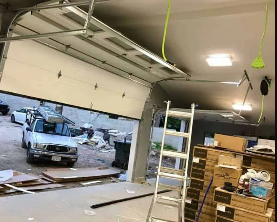 Technician repairing a garage door with the Alum Creek Garage Doors Repair van in the background, showcasing local garage door repair services.