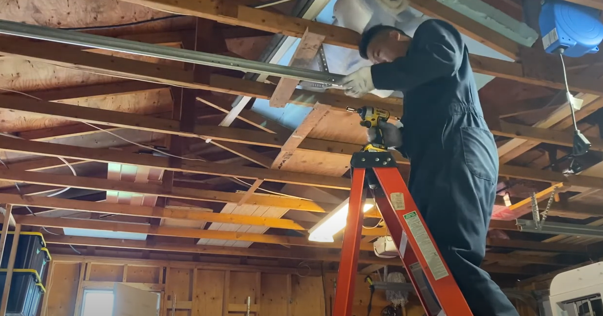 Technician aligning and adjusting a garage door track during a garage door track repair to ensure smooth operation.