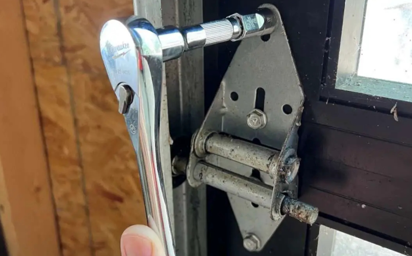 Technician performing a noisy garage door repair on a residential property in Alum Creek, using professional tools to fix the garage door mechanism.