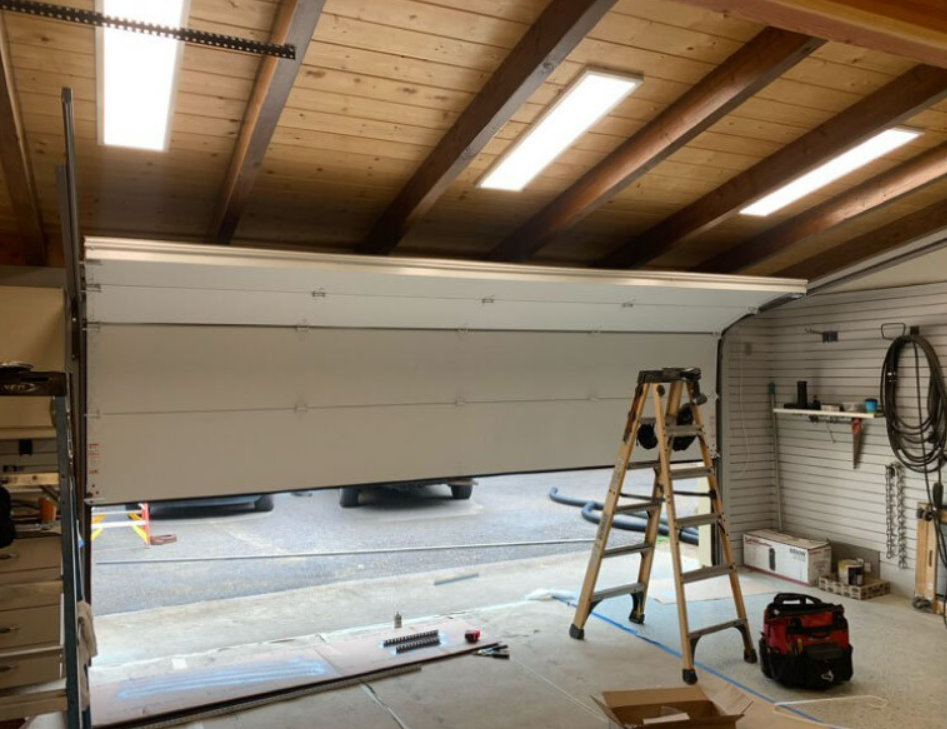 Technician performing overhead garage door repair for a residential property, showcasing tools and machinery used in Alum Creek Garage Doors Repair services