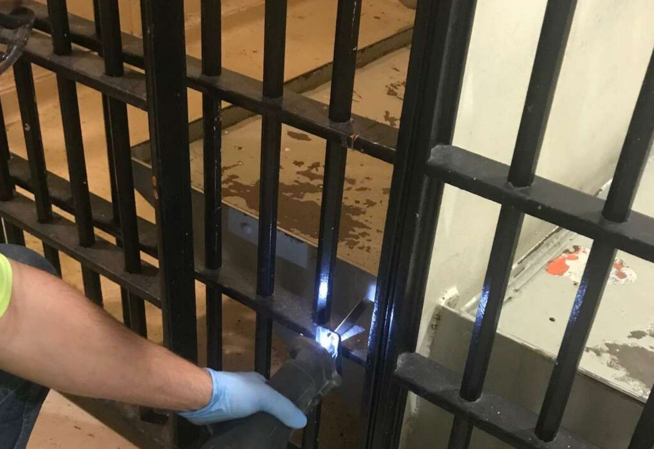 Technician repairing a commercial gate with tools, showcasing professional service by Alum Creek Garage Doors Repair
